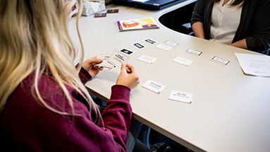 Student sits with career coach at desk doing a card sorting activity.