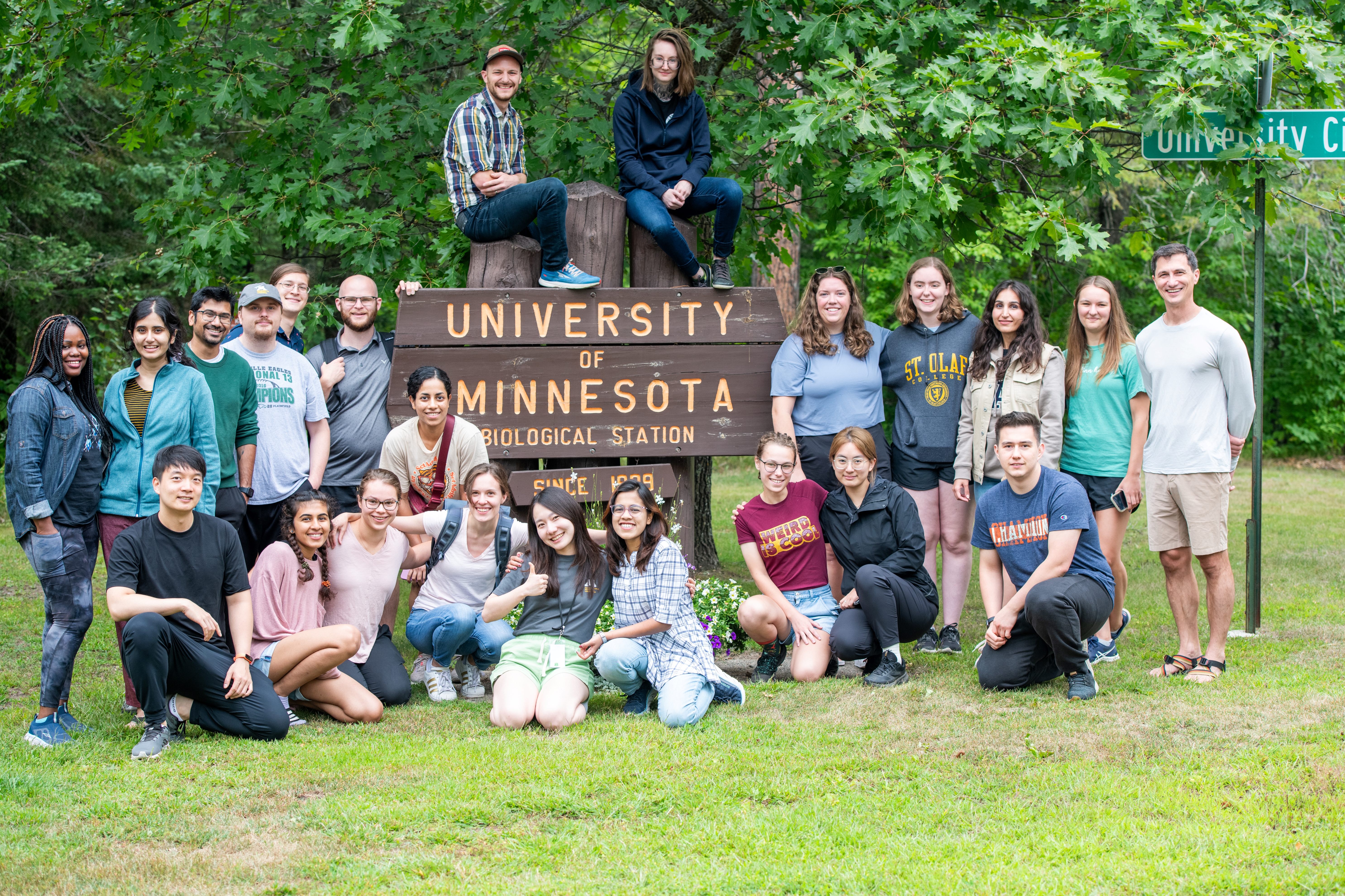 a group of people at the U of M Biological Station sign at the entrance of the Itasca Biological Station