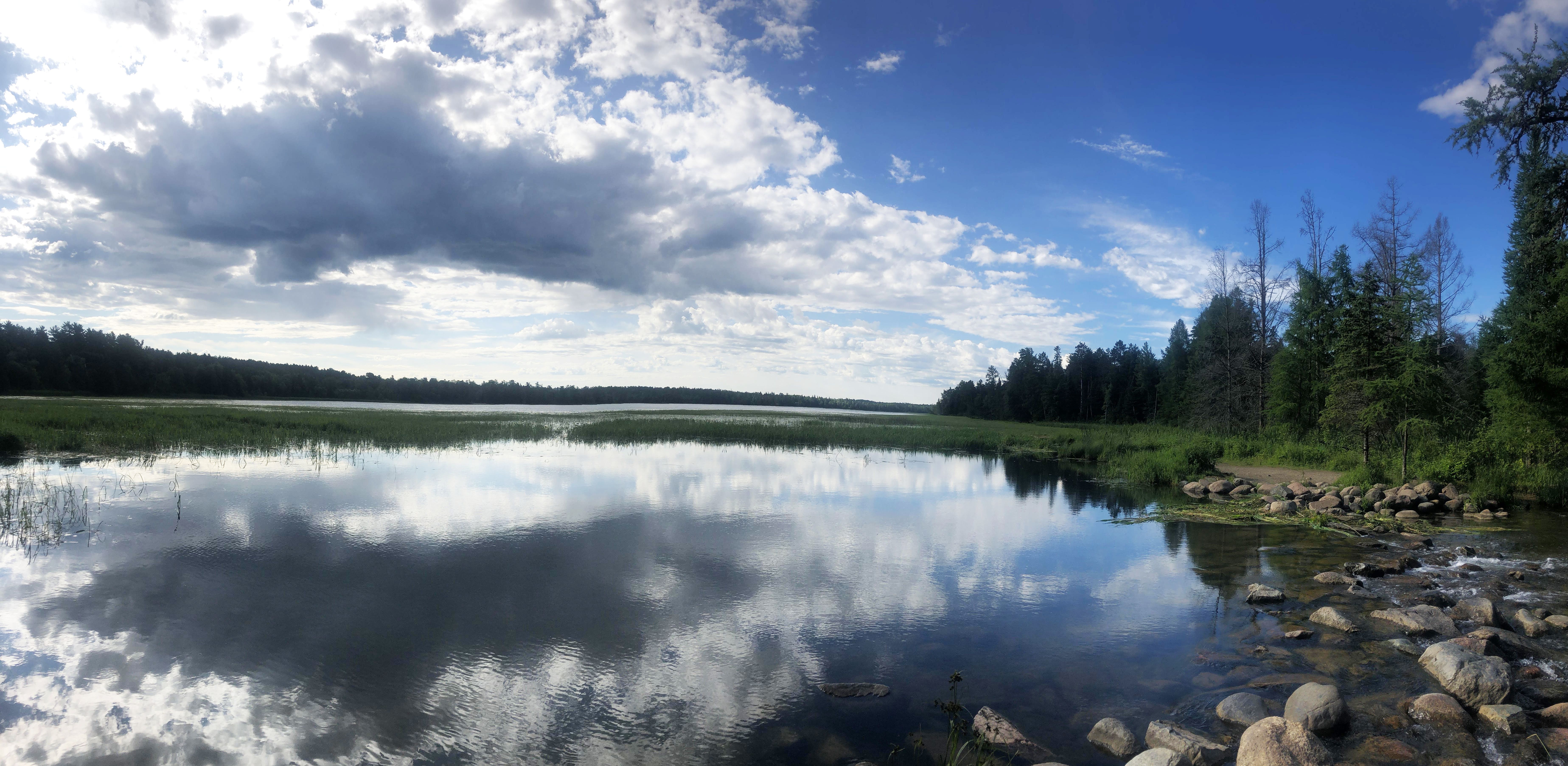 The Lake Itasca Mississippi Headwaters on a sunny day, with the clouds in the sky reflecting on the lake