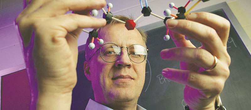 Faculty member holding a 3-d molecular structure