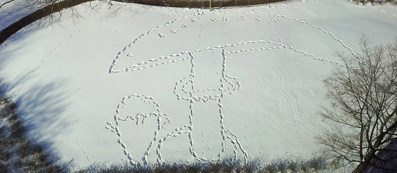 Snowy field with footprints making the outline of a mushroom