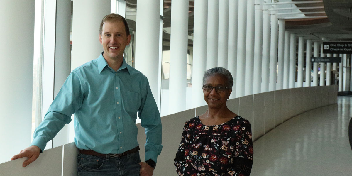 Cheryl Scott and Brian Gibbens stand together in long hallway