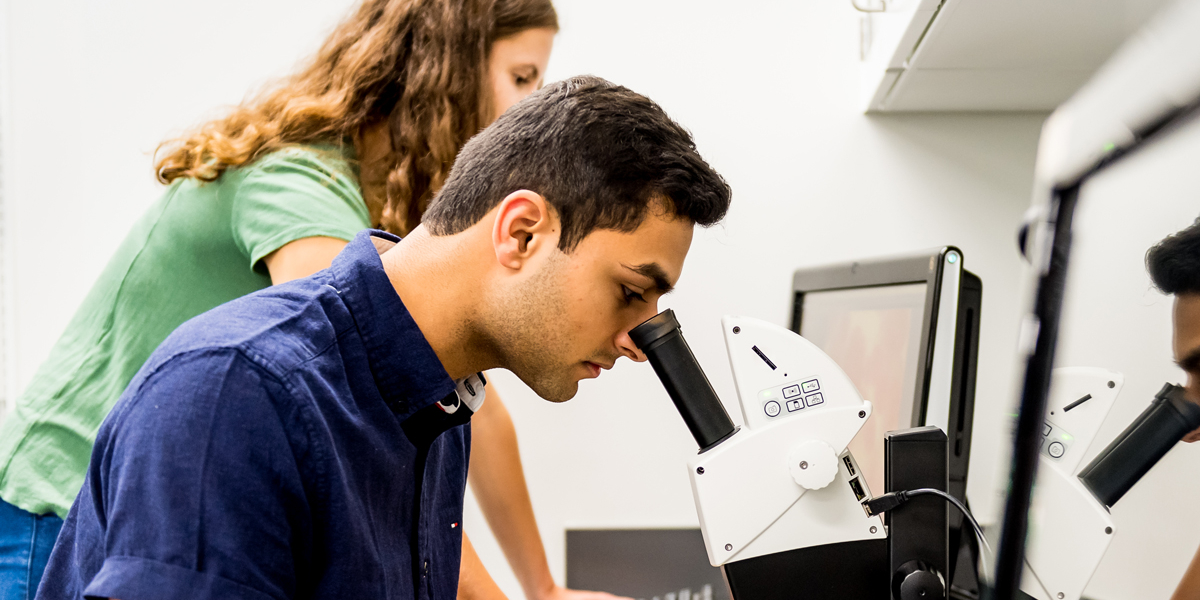 Students looking at microscope and computer