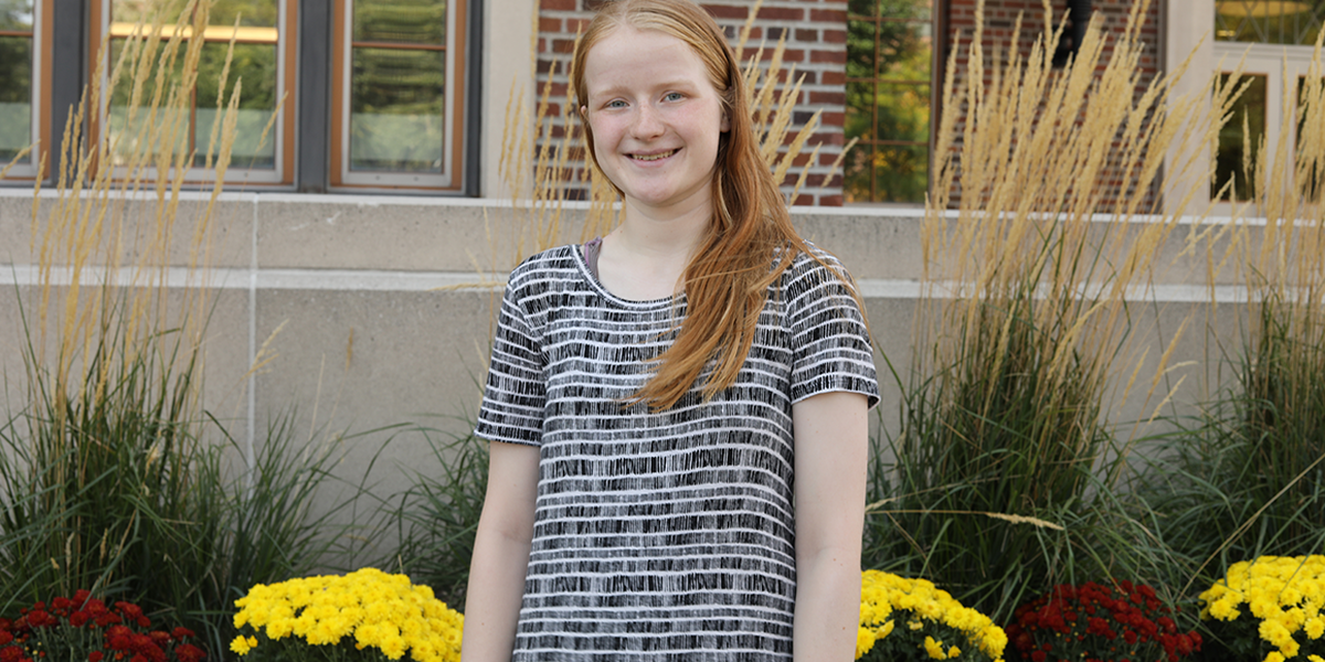 Mikayla poses outside building with flowers