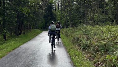 Two people bike down path in the woods at Itasca State Park